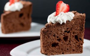 chocolate cake, cream and strawberry on it